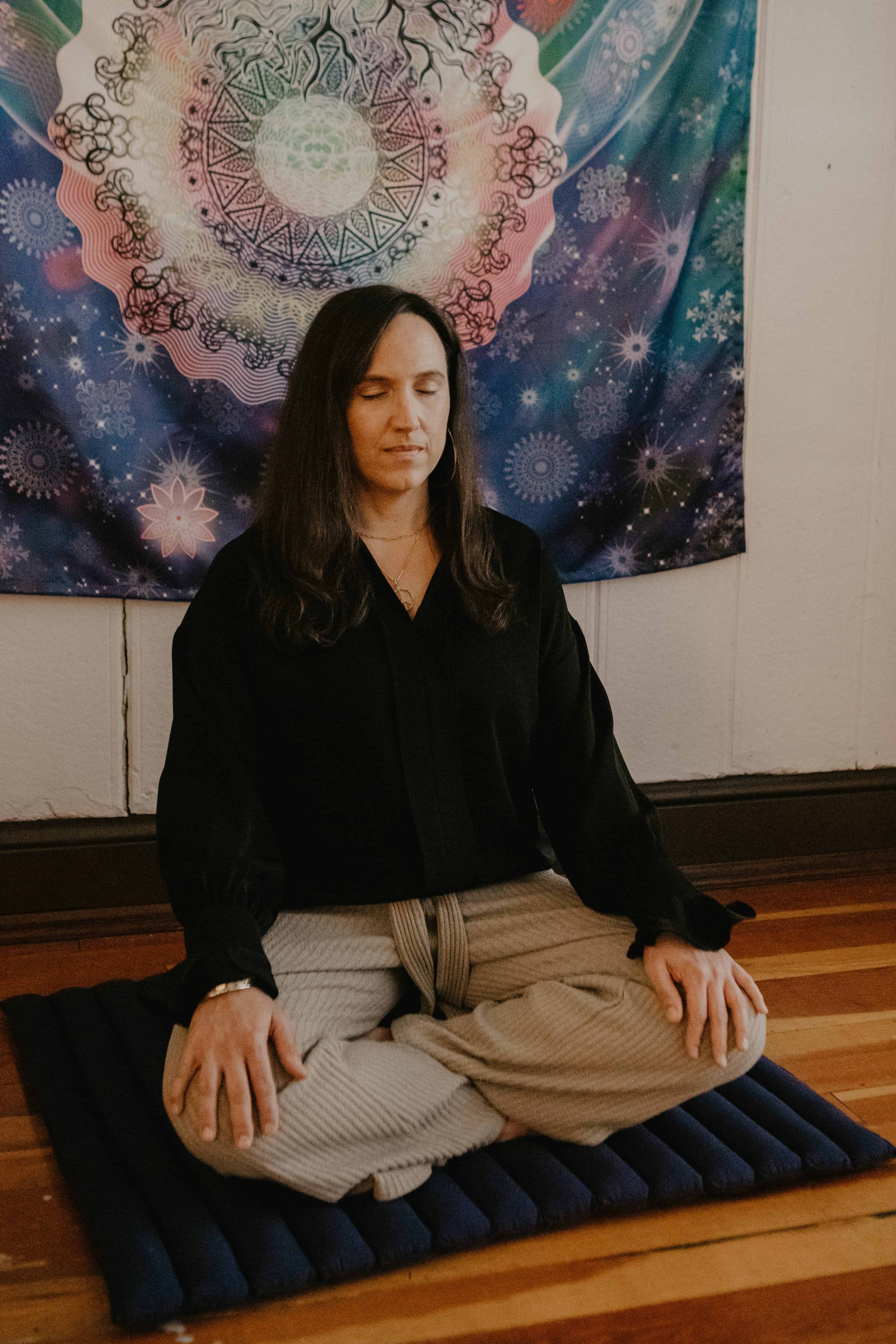 leah martinson, integrative life coach, sits cross legged in meditation in her studio